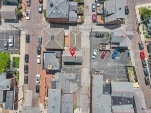 An aerial view of a parking lot with multiple cars, buildings, and a red traffic sign.