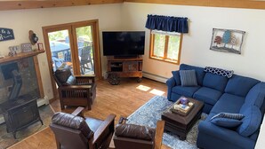 A cozy living room with a blue sofa, leather chairs, a TV, and a fireplace.
