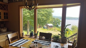 A dining area with a wooden table set for four, two black and white checkered placemats, and potted plants on the windowsill.