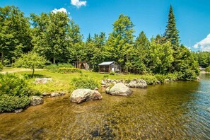 A cabin by a clear stream surrounded by dense trees. - Amazing large home located at Cricket Cove on Maidstone Lake, Vermont (Maidstone)