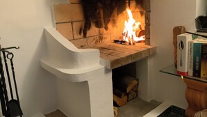 A fireplace with a brick surround and a white mantel, with books on a nearby shelf.