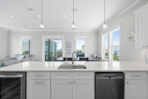 A modern kitchen with a large island, white cabinetry, and pendant lighting. - 5BR Gulf View Home w/ Private Pool • Big Beach Views • Family Retreat (Port St Joe)