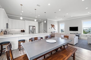Une cuisine moderne avec des meubles blancs, un îlot central et des luminaires suspendus.