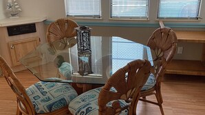 A dining area with a glass-top table surrounded by wicker chairs with patterned cushions. - Relaxing and Inviting home in gated community with 35' Seawall Private Dock (Cudjoe Key)