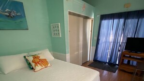 A hotel room with a bed, a ceiling fan, a television, and a door leading to a balcony. - Relaxing and Inviting home in gated community with 35' Seawall Private Dock (Cudjoe Key)