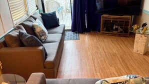 A living room with a sofa, a television, and a view of the outside. - Relaxing and Inviting home in gated community with 35' Seawall Private Dock (Cudjoe Key)