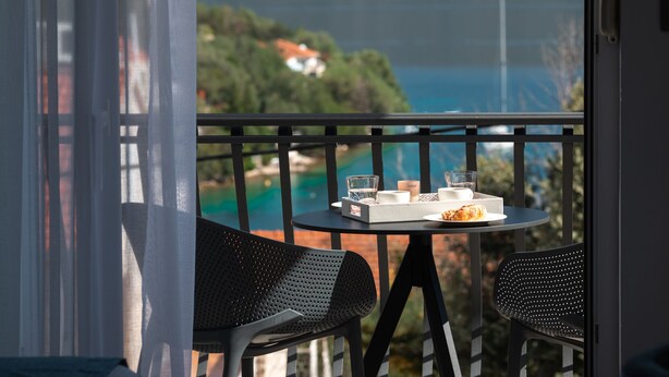 A balcony with a table set for two, overlooking a coastal landscape. - WISH Apartments (Korcula)