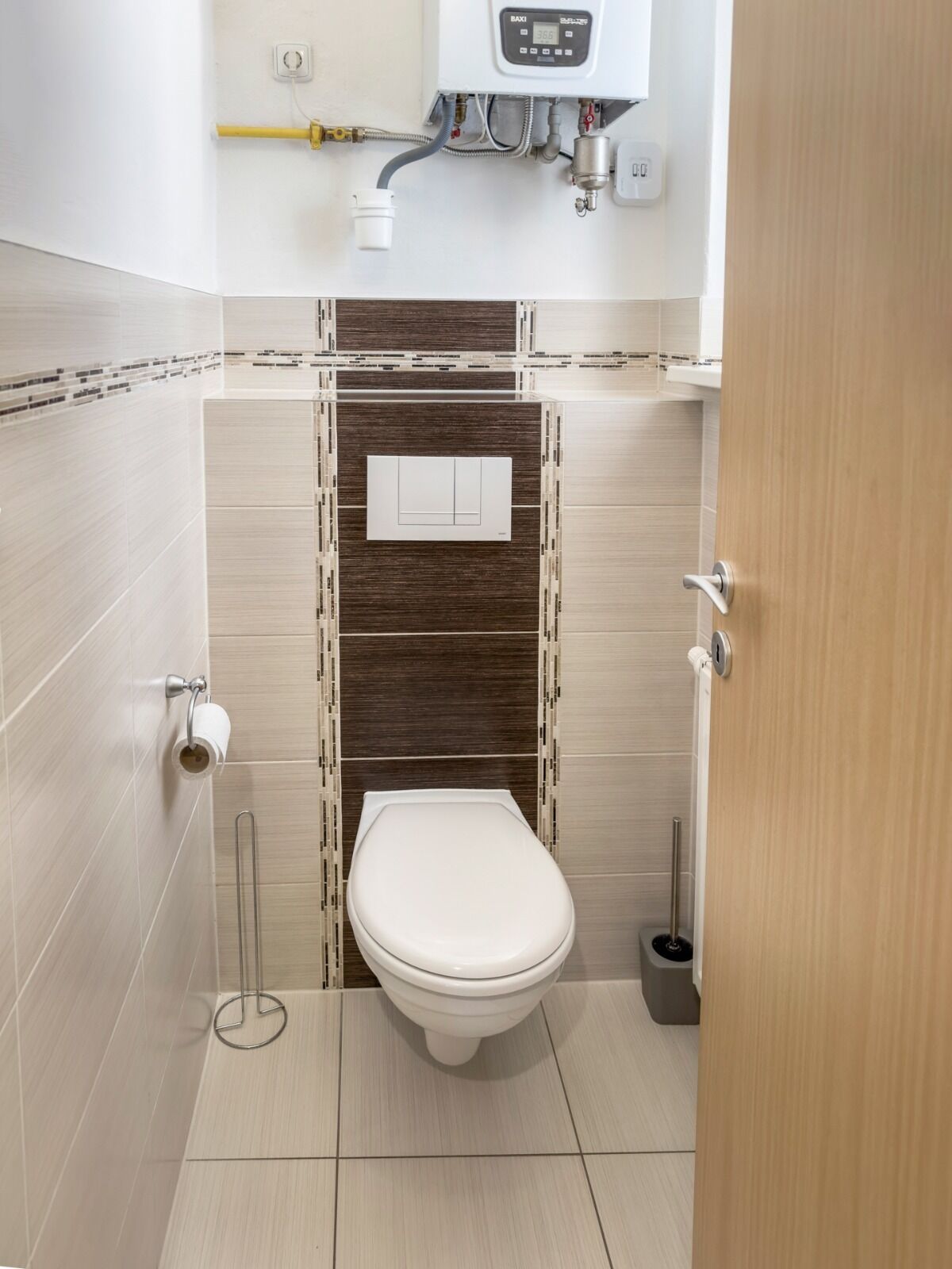 A small, modern bathroom with a toilet, a toilet paper holder, a bidet, and a toilet brush.