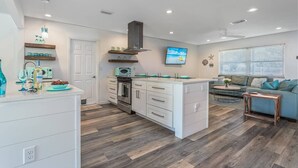 A modern kitchen with white cabinetry, a central island, and a dining area with a blue sofa and a small table.