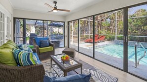 A sunlit patio with wicker furniture, a pool, and a view of the outdoors. - Toes in the Water - Pool Home on Siesta Key (Siesta Key)