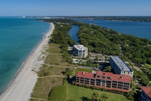 An aerial view of a coastal property with a beach, a river, and a large building with a red roof. - Bay Tree Beach Side (Siesta Key)