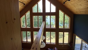 Ein Zimmer mit großen Fenstern, Holzbalkendecke und Deckenventilator.