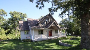 Ein eingeschossiges Haus mit Satteldach, einer Veranda und einer roter Tür.