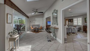 A spacious living area with a high ceiling, a ceiling fan, and a skylight. There is a dining area with a table and chairs, and a kitchen area with a countertop and sink. - Canopy Cottage on Siesta Key (Siesta Key)