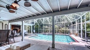 A covered outdoor area with a pool, lounge chairs, and a view of the surrounding greenery. - Canopy Cottage on Siesta Key (Siesta Key)