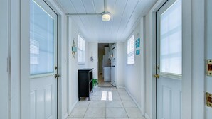 Un couloir avec des portes blanches, un luminaire au plafond et un sol carrelé.