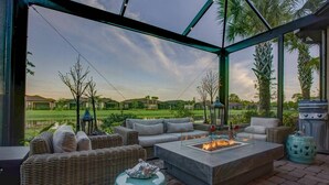 Um pátio externo com mobiliário de vime, lareira e vista para um campo de golfe.