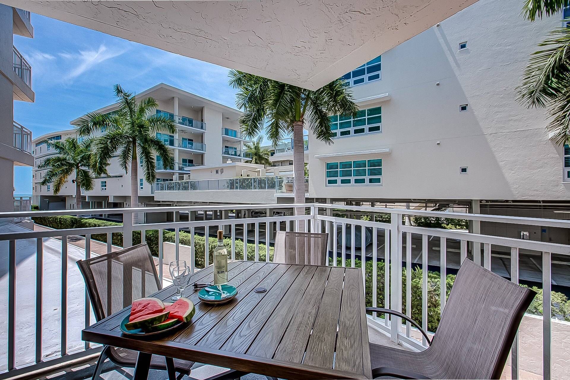 A balcony with a wooden table, chairs, and a plate of watermelon slices.