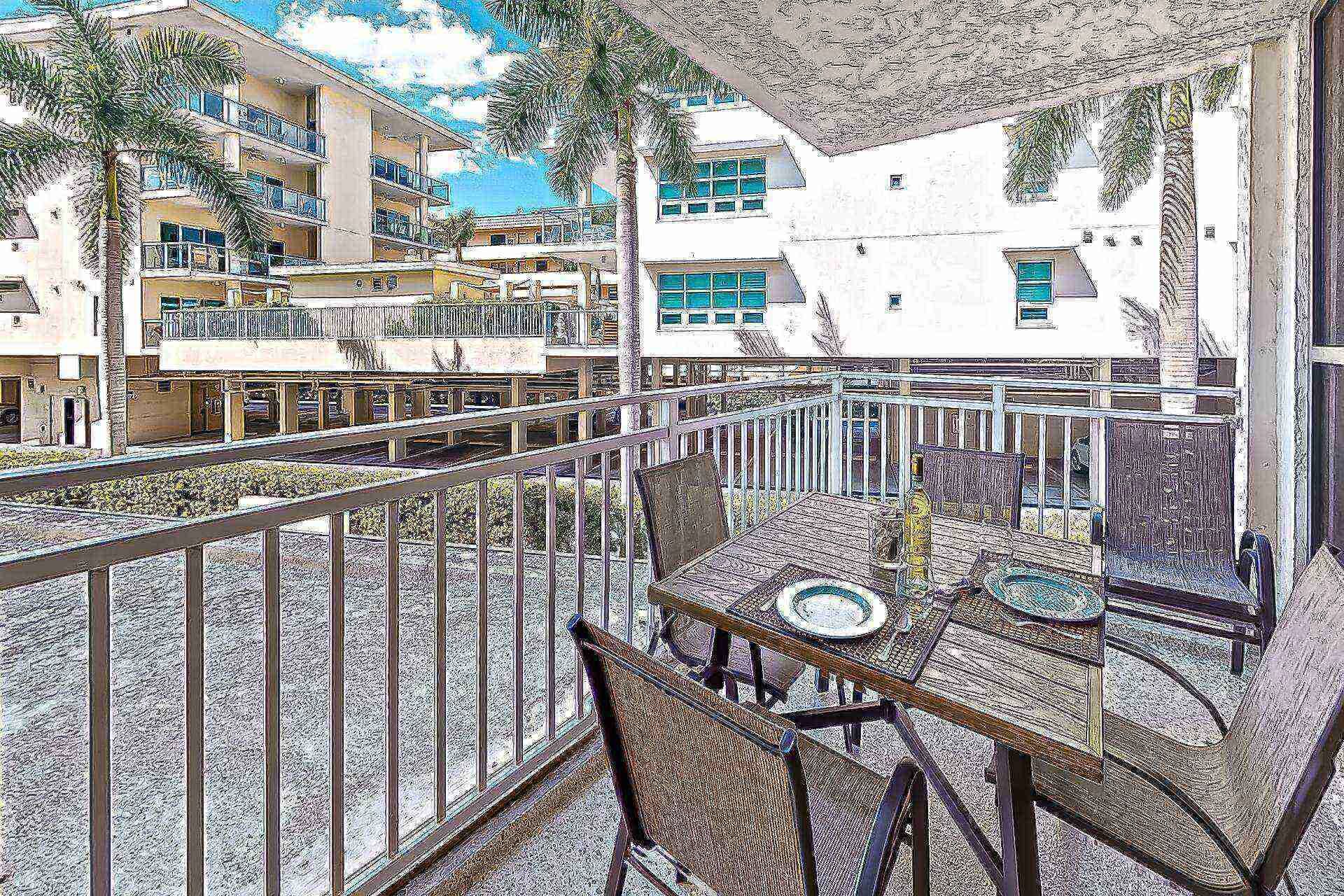 A balcony with outdoor furniture, a railing, and a view of multi-story buildings with balconies and windows.