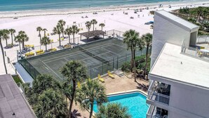 Un hotel con cancha de tenis, piscina y vista al mar.