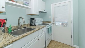 A compact kitchen with a sink, stove, and coffee maker. - Island Dreams Gulf Breeze #2 (Sarasota)