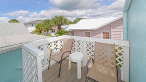 A balcony with a white lattice fence, two white plastic chairs, and a small round table. - Island Dreams Gulf Breeze #2 (Sarasota)