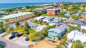 An aerial view of a coastal residential area with various buildings, including a hotel with a green roof and a beachside location. - Island Dreams Gulf Breeze #2 (Sarasota)