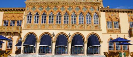 Un edificio histórico con arquitectura gótica ornamentada, que presenta una entrada central en arco y un patio con azulejos.