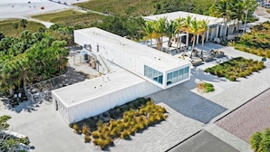 A modern building with a flat roof, large windows, and a covered outdoor area with seating. - Minorga Sand Dollar on the Key (Siesta Key)