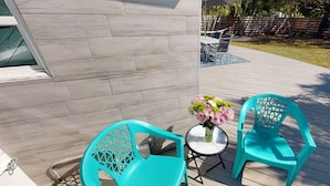 A patio with turquoise chairs and a small round table with a vase of flowers. - Modern Grove Duplex Unit B (Sarasota)