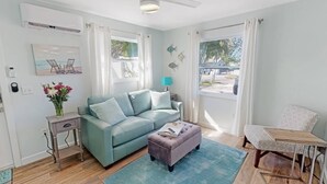A living room with a light blue sofa, a small table, a coffee table, and a view of the outside. - Modern Grove Duplex Unit B (Sarasota)
