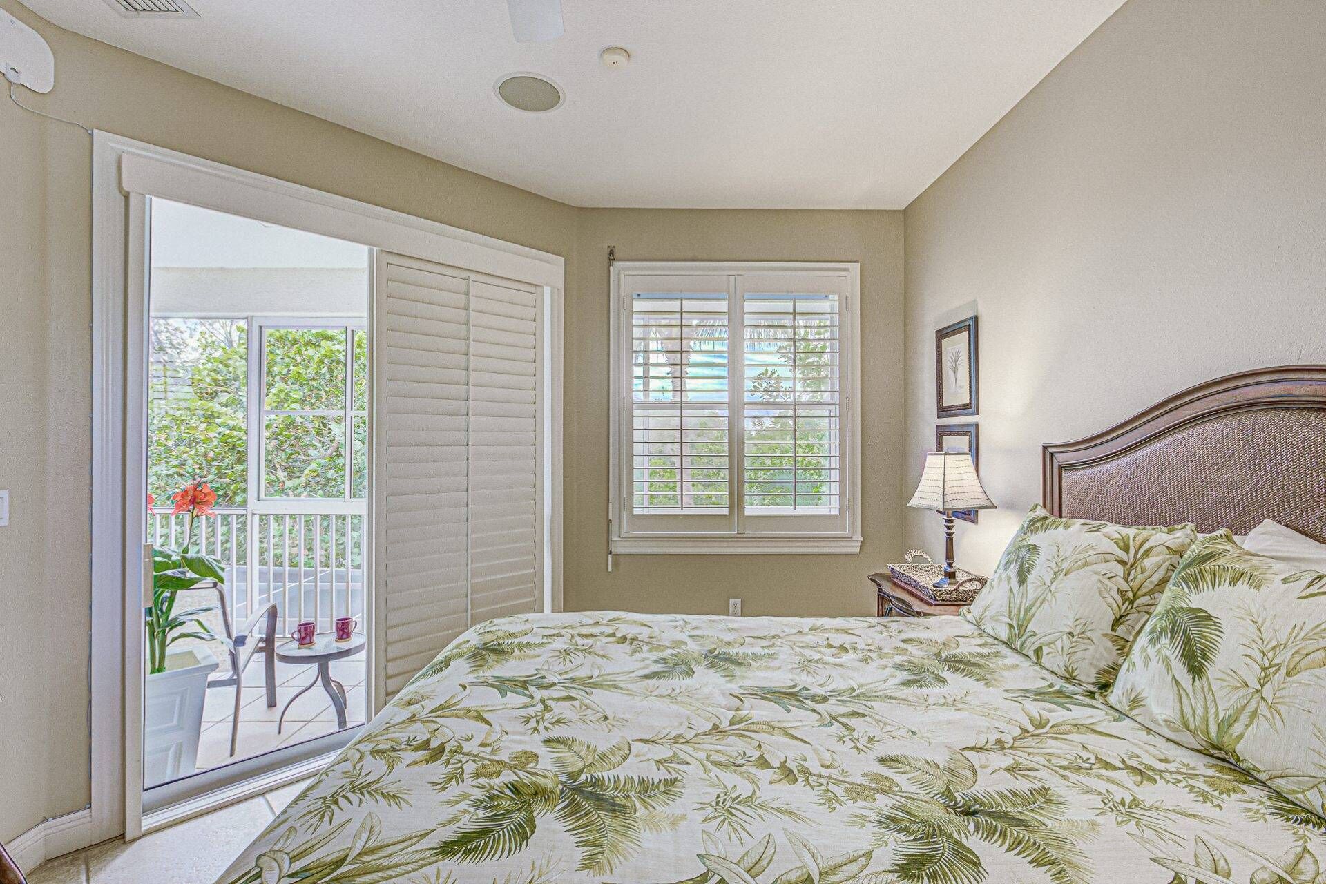 A bedroom with a bed, a window, a nightstand, and a chair by the window.