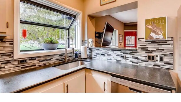 A modern kitchen with a large window, a built-in sink, and a backsplash with geometric tiles. - Mid-Century 3 Bdr Lakewood Home Mountain Access! (Lakewood)