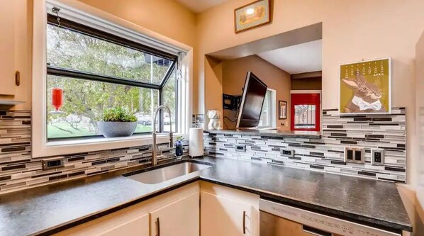 A modern kitchen with a large window, a built-in sink, and a backsplash with geometric tiles.