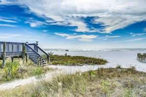 A wooden boardwalk leading to a beach with a clear view of the ocean and distant boats. - Serene Casarina (Siesta Key)