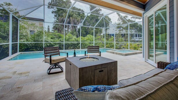 Ein überdachter Außenbereich mit Pool, Holzmöbeln und einer Glaskonstruktion.