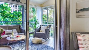 A room with a view of a balcony, wicker furniture, and a bottle of wine on a table. - Siesta Bayside Condo 3 Bedroom (Siesta Key)