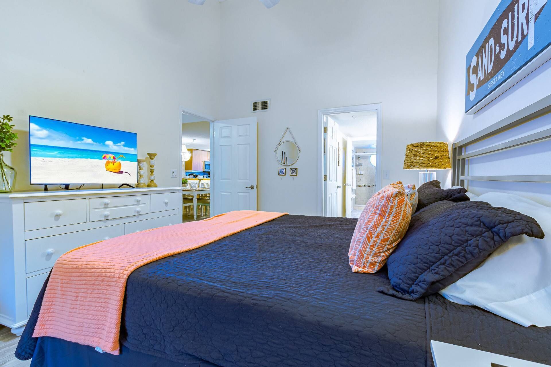 Une chambre à coucher avec un lit, une commode, un téléviseur et un panneau accroché au mur.