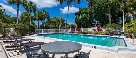 A pool area with lounge chairs, a table, and a sign indicating a 3 FT depth.