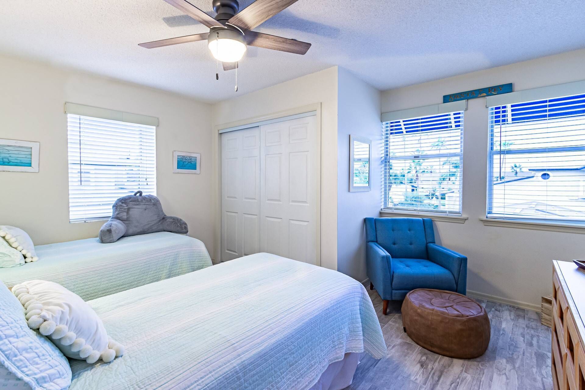 A bedroom with two beds, a ceiling fan, and a window with blinds.