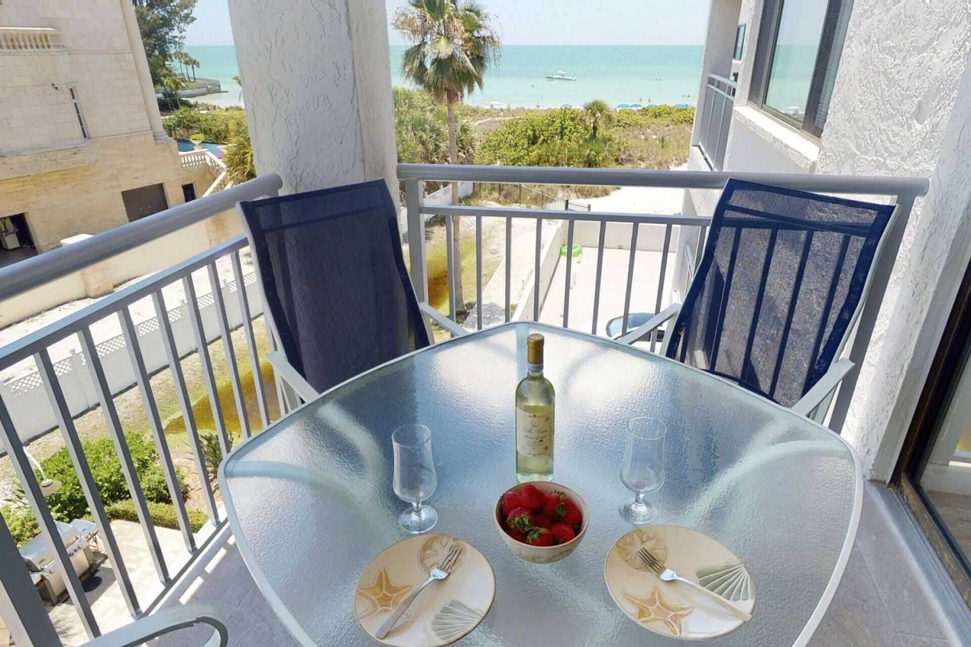 Un balcon avec une table dressée pour deux personnes, donnant sur une plage.