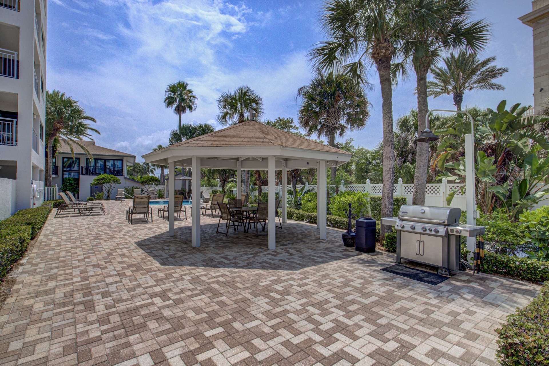 A covered patio area with outdoor seating, a barbecue grill, and a pool.