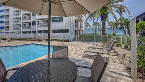 Un espace aménagé au bord de la piscine, comprenant une piscine, des chaises longues et un parasol.