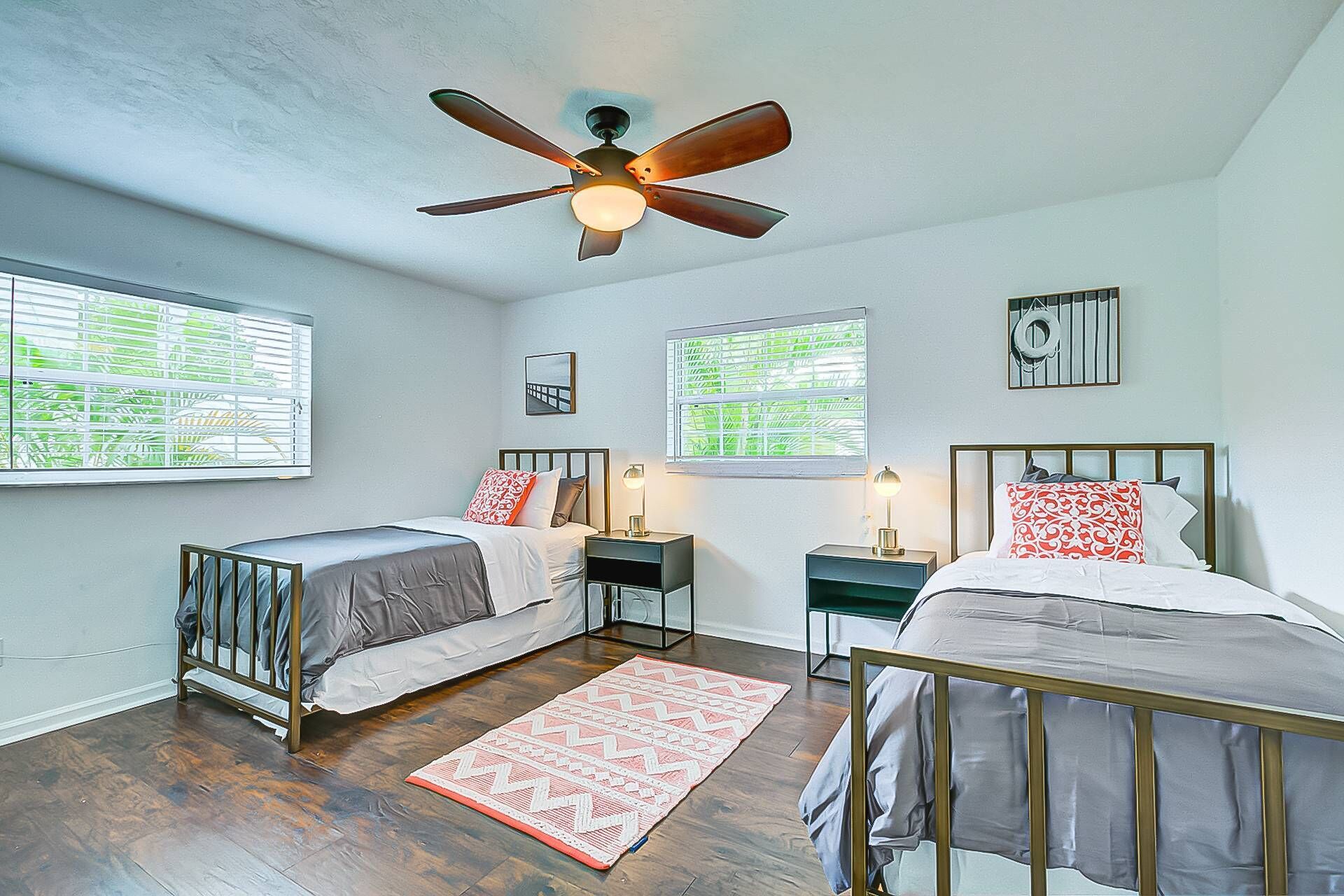 A bedroom with two beds, a ceiling fan, and two bedside tables with lamps.
