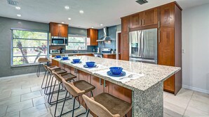 Una cocina moderna con encimera de granito, electrodomésticos de acero inoxidable y armarios de madera.