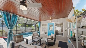 Un espacio al aire libre cubierto con piscina, techo de madera y ventanas grandes con cortinas azules.