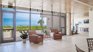 En rummelig lobby med store vinduer der giver udsigt over stranden og havet. Der er komfortable siddepladser og et løbebånd.