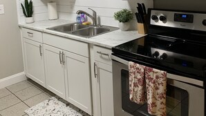 A kitchen with white cabinets, a stainless steel microwave, a stove, and a sink. - Cozy getaway! Minutes from Historic Pinellas Trail! (Largo)