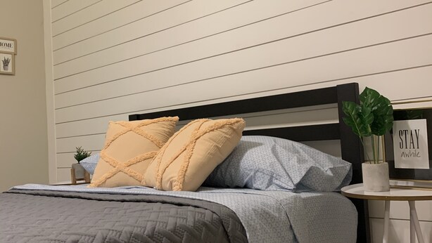 A bedroom with a bed, a bedside table with a plant, and a sign that says "STAY awhile". - Cozy getaway! Minutes from Historic Pinellas Trail! (Largo)