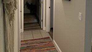 A hallway with a patterned rug, a framed picture on the wall, and a light fixture. - Cozy getaway! Minutes from Historic Pinellas Trail! (Largo)